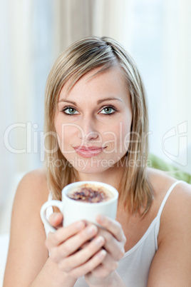Portrait of a young woman drinking a coffee sitting on a sofa