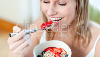 Charming woman eating muesli with fruits