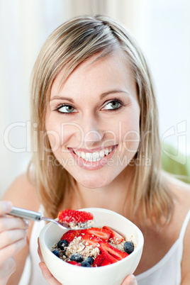 Delighted woman eating muesli with fruits