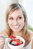 Delighted woman eating muesli with fruits