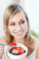 Cheerful woman eating muesli with fruits