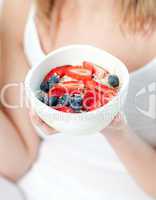 Blond woman holding a bowl of muesli with fruits