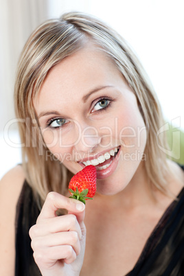 Smiling woman eating a strawberry