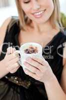 Blond woman drinking a coffee sitting on a sofa