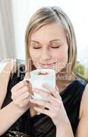 Relaxed woman drinking a coffee sitting on a sofa