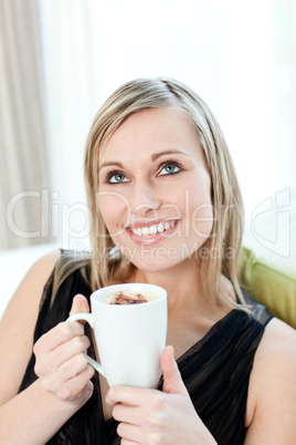 Radiant woman drinking a coffee sitting on a sofa