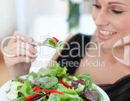 Close-up of a smiling woman eating a salad