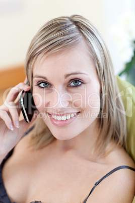 Radiant woman talking on phone sitting on a sofa