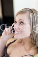 Charming woman talking on phone sitting on a sofa