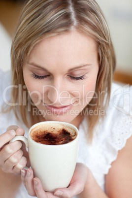 Young woman drinking a coffee sitting on a sofa