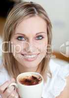 Charming woman drinking a coffee sitting on a sofa