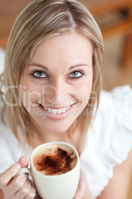 Bright woman drinking a coffee sitting on a sofa