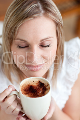 Attractive woman drinking a coffee sitting on a sofa