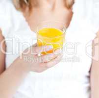 Close-up of a young woman holding an orange juice