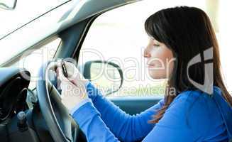 Attractive teen girl using a mobile phone while driving