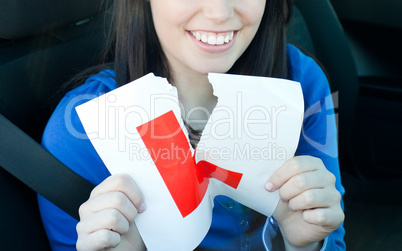 Charming teen girl sitting in her car tearing a L-sign
