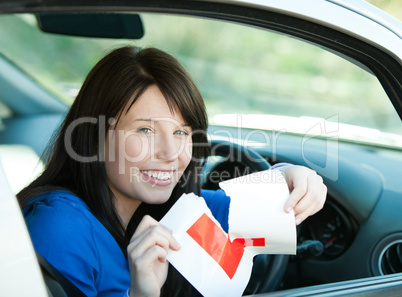 Charming brunette teen girl sitting in her car tearing a L-sign