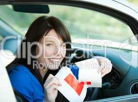 Charming brunette teen girl sitting in her car tearing a L-sign