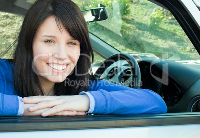 Happy teen girl smiling at the camera sitting in her car