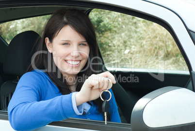 Happy teen girl sitting in her car holding keys