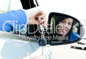 Cheerful teen girl sitting in her car holding keys