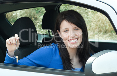 Jolly teen girl sitting in her car holding keys