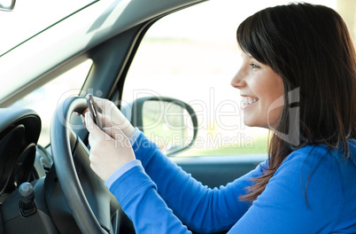 Smiling teen girl using a mobile phone while driving