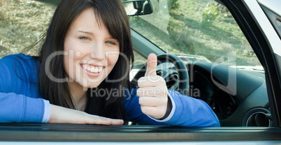 Happy teen girl with a thumb up sitting in her car