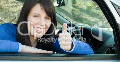 Happy teen girl with a thumb up sitting in her car