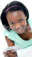 Smiling young woman holding a credit card lying on a bed