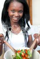 Smiling Afro-american woman preparing a salad