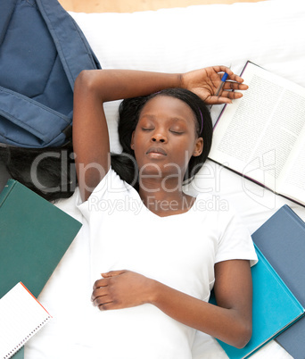 Tired student doing her homework lying on a bed