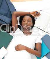 Tired student doing her homework lying on a bed