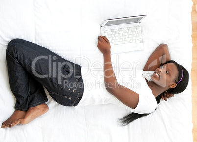 Happy woman surfing the internet lying on a bed