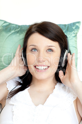 Cheerful woman listening music lying on a sofa