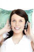 Cheerful woman listening music lying on a sofa