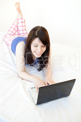 Relaxed woman surfing the internet lying on a bed