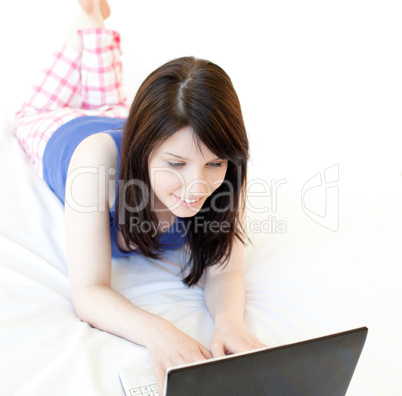 Young woman surfing the internet lying on a bed