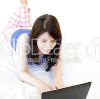 Young woman surfing the internet lying on a bed