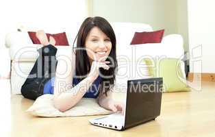 Joyful woman surfing the internet lying on the floor