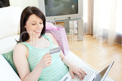 Attractive young woman shopping on-line lying on a sofa