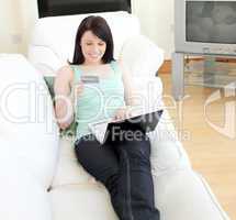 Charming woman shopping on-line lying on a sofa