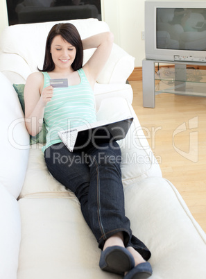 Young woman shopping on-line lying on a sofa