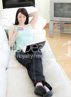 Young woman shopping on-line lying on a sofa