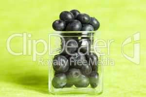 blueberries in a glass jar on a green background
