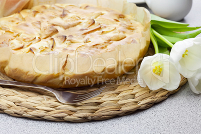 apple pie, fork and tulips on a woven mat