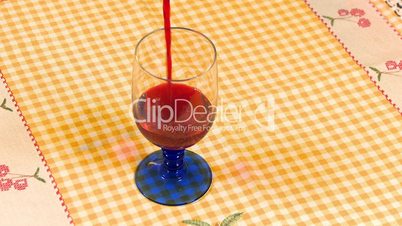 Red wine poured into the glass on table