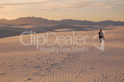 walker on dunes at sunset