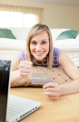 Successful woman shopping on-line lying on the floor