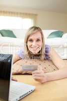 Happy woman shopping on-line lying on the floor